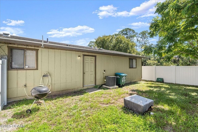 back of house featuring fence, central AC unit, and a lawn