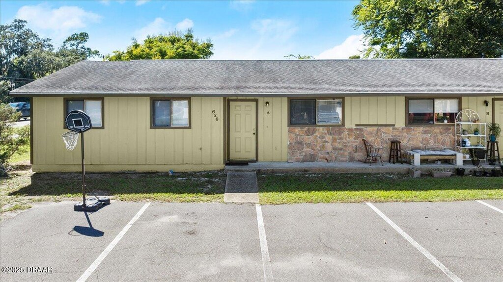 638 Lpga Blvd Unit A, Daytona Beach, FL 32117 - ranch-style house with stone siding, a shingled roof, and uncovered parking