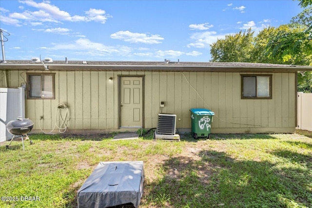 rear view of property featuring central AC, a yard, and fence