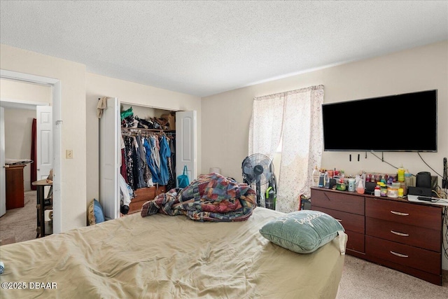 bedroom with a closet, a textured ceiling, and light colored carpet