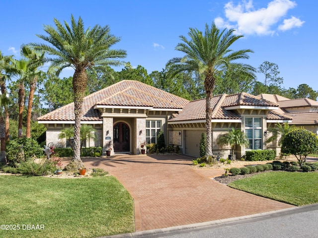 mediterranean / spanish house featuring a garage and a front lawn