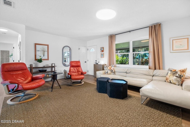 living room with arched walkways, visible vents, and wood finished floors