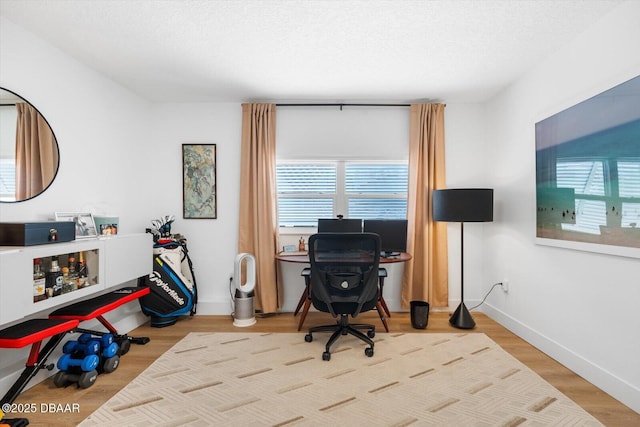 office area with wood finished floors, a textured ceiling, baseboards, and a wealth of natural light