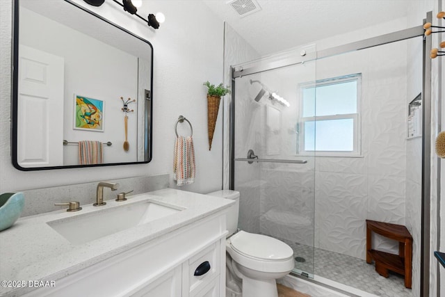 full bath with vanity, toilet, a shower stall, a textured ceiling, and visible vents