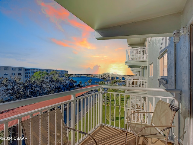 balcony at dusk featuring a water view