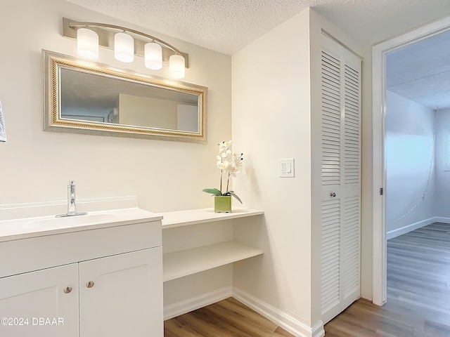 bathroom featuring vanity, wood-type flooring, and a textured ceiling