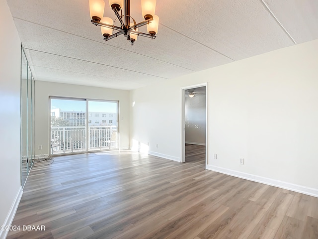 unfurnished room featuring hardwood / wood-style floors, ceiling fan with notable chandelier, and a textured ceiling