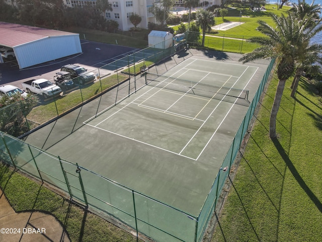 view of tennis court featuring basketball hoop and a yard