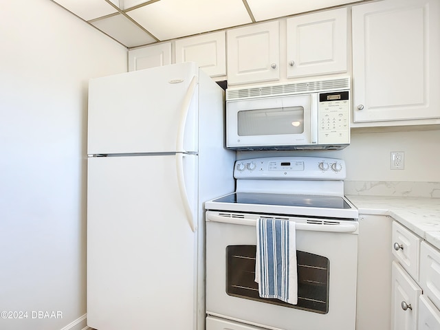 kitchen featuring light stone countertops, white cabinets, and white appliances