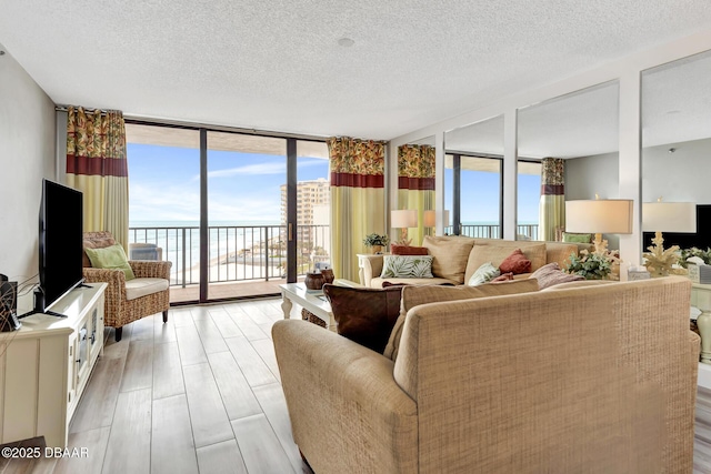 living room featuring light hardwood / wood-style floors, a wall of windows, and a textured ceiling