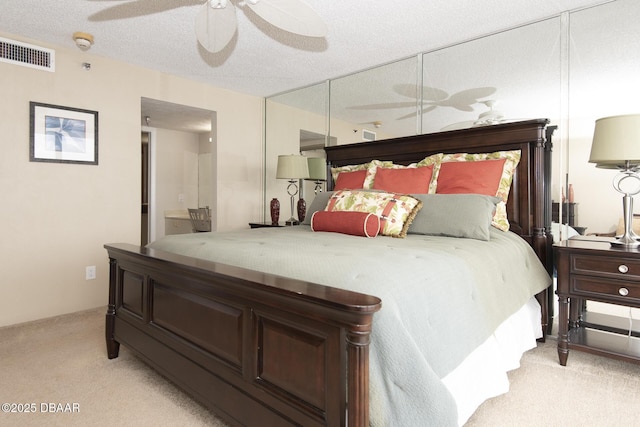 bedroom featuring a textured ceiling, ceiling fan, and light carpet