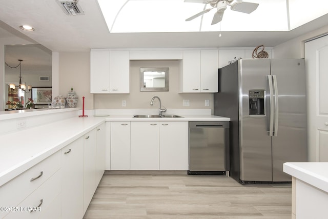 kitchen featuring white cabinets, appliances with stainless steel finishes, decorative light fixtures, and sink