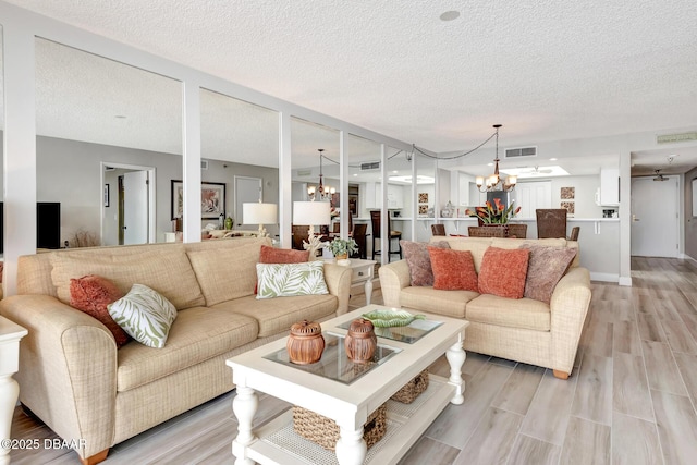 living room featuring a chandelier, a textured ceiling, and light hardwood / wood-style flooring