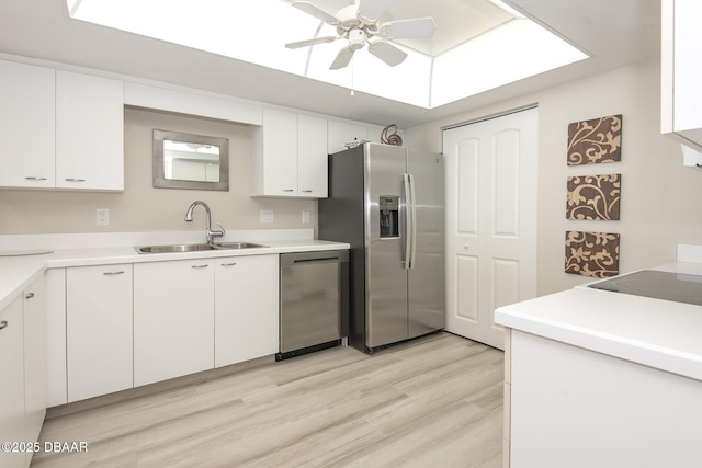 kitchen featuring white cabinets, sink, ceiling fan, light wood-type flooring, and appliances with stainless steel finishes