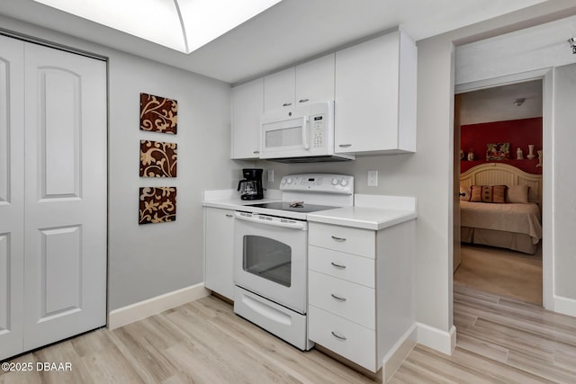 kitchen featuring white cabinets, light wood-type flooring, and white appliances