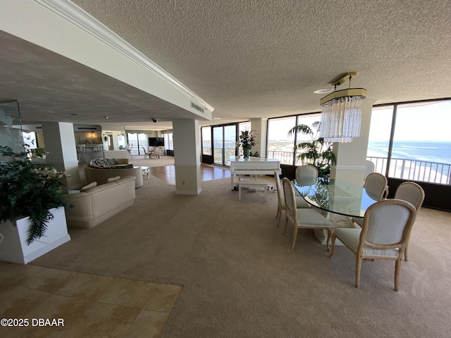 carpeted dining room with a water view, crown molding, a textured ceiling, a notable chandelier, and a wall of windows