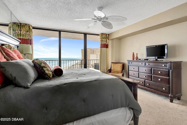 bedroom featuring access to outside, ceiling fan, a textured ceiling, light colored carpet, and a wall of windows