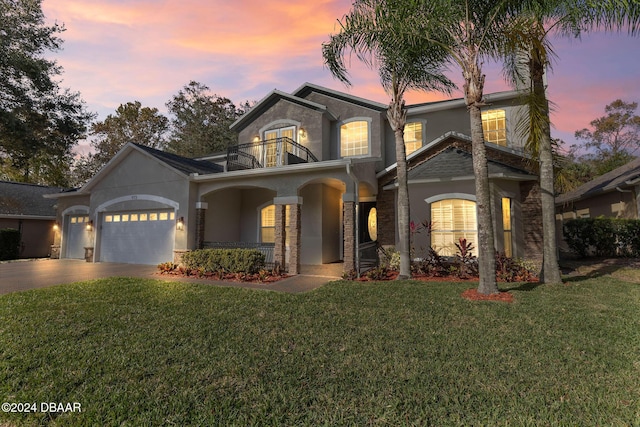 view of front of house with a balcony, a garage, and a lawn