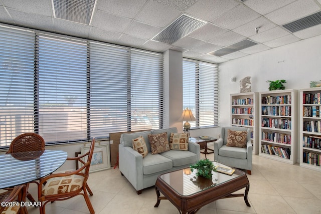 living room featuring a paneled ceiling and light tile patterned flooring