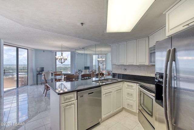 kitchen featuring stainless steel appliances, an inviting chandelier, kitchen peninsula, a textured ceiling, and decorative backsplash