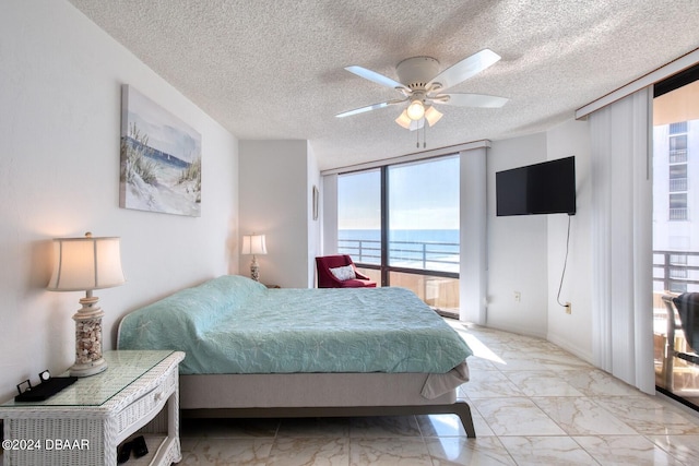 bedroom featuring ceiling fan, floor to ceiling windows, and a textured ceiling