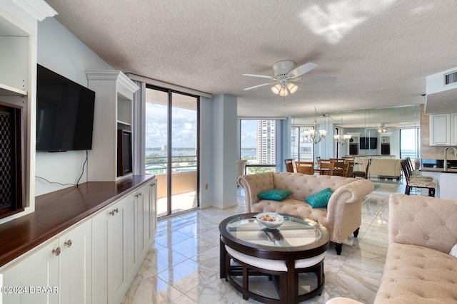 living room featuring ceiling fan with notable chandelier, a textured ceiling, and floor to ceiling windows