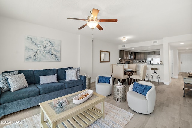 living room with ceiling fan and light hardwood / wood-style flooring