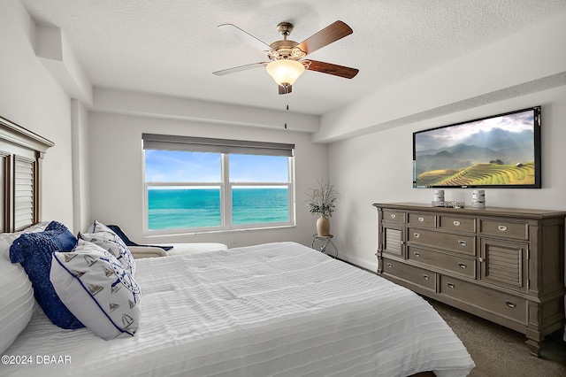 bedroom with dark colored carpet, a textured ceiling, and ceiling fan