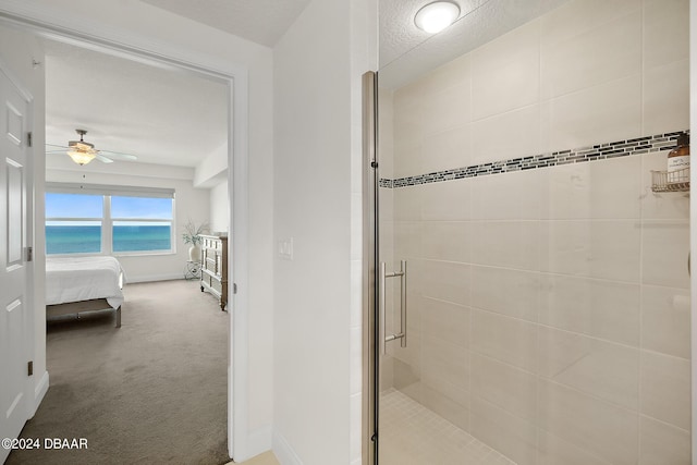 bathroom featuring a water view, ceiling fan, and a shower with door