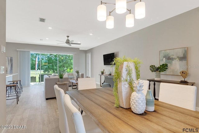 dining room with light hardwood / wood-style flooring and ceiling fan with notable chandelier