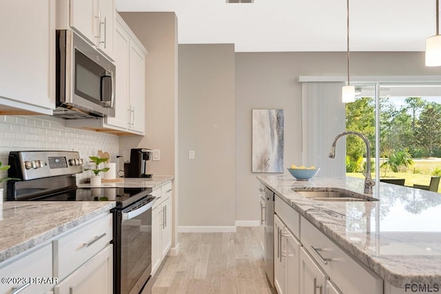 kitchen featuring sink, light stone countertops, light wood-type flooring, appliances with stainless steel finishes, and white cabinetry