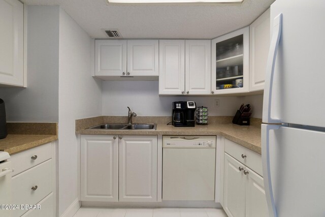 kitchen featuring white cabinetry, sink, white appliances, and light tile patterned floors