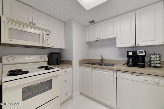 kitchen with white cabinets, sink, white appliances, and light tile patterned floors