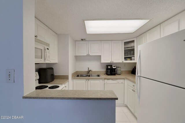 kitchen with sink, kitchen peninsula, a textured ceiling, white appliances, and white cabinets