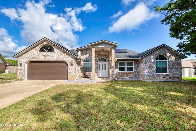 view of front of property featuring a front lawn, a garage, and solar panels