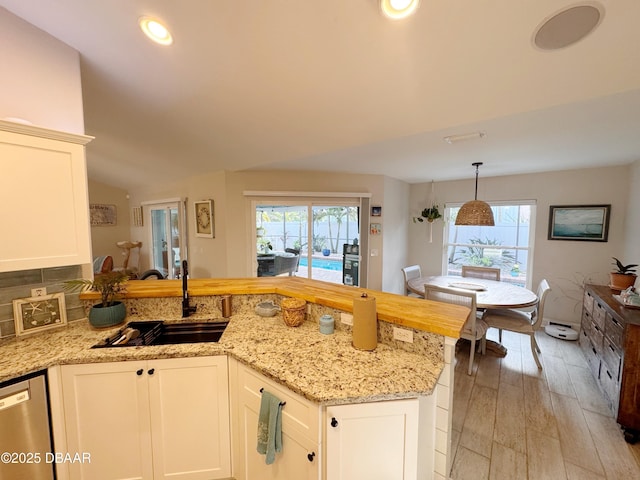 kitchen featuring light stone counters, a healthy amount of sunlight, a sink, and stainless steel dishwasher