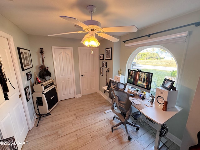 office featuring light wood finished floors, a ceiling fan, and baseboards