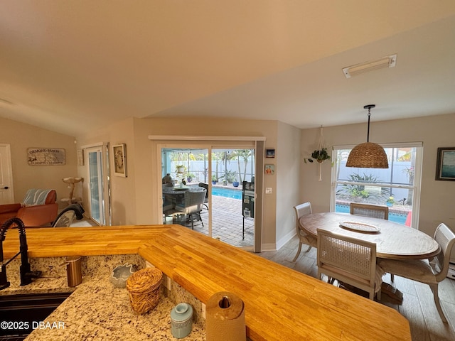 dining space featuring lofted ceiling, wood-type flooring, visible vents, and a wealth of natural light