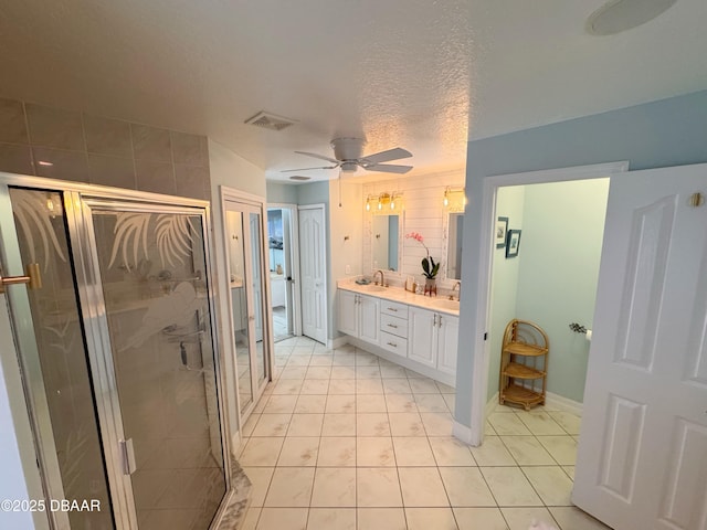 bathroom featuring double vanity, visible vents, a stall shower, a textured ceiling, and tile patterned flooring