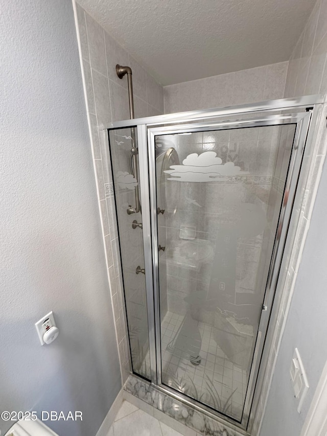 full bathroom with a stall shower, baseboards, a textured wall, tile patterned flooring, and a textured ceiling