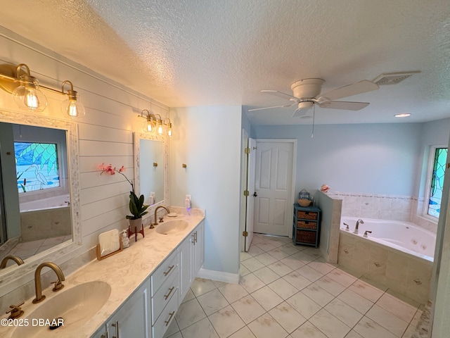 bathroom with double vanity, visible vents, a sink, and a bath