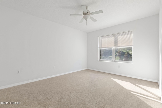 empty room with carpet floors, a textured ceiling, baseboards, and a ceiling fan