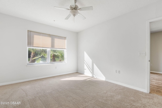 empty room featuring a ceiling fan, light colored carpet, a textured ceiling, and baseboards