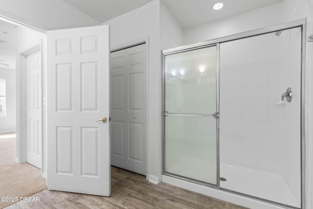 bathroom with a shower stall, a closet, and wood finished floors