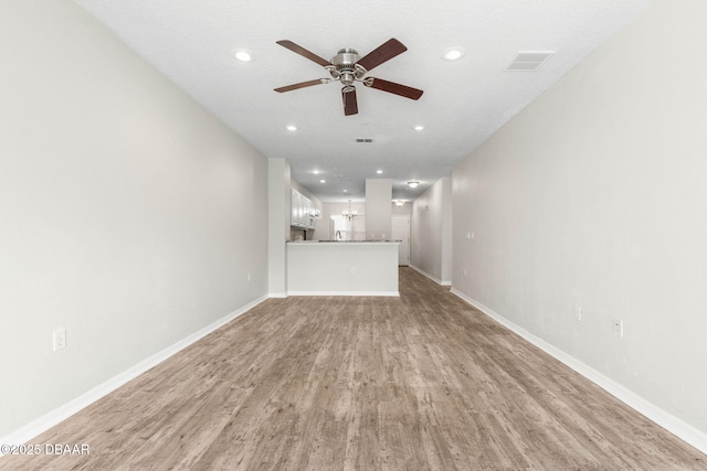 unfurnished living room with light wood finished floors, recessed lighting, visible vents, a ceiling fan, and baseboards