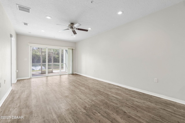 empty room with baseboards, visible vents, and wood finished floors