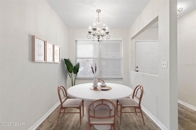 dining room with an inviting chandelier, baseboards, and wood finished floors