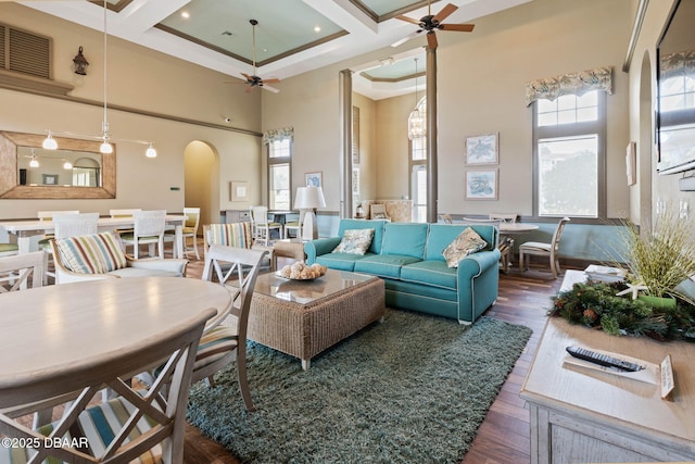 living room featuring a healthy amount of sunlight, a high ceiling, arched walkways, and coffered ceiling