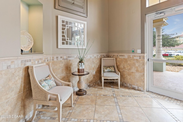 sitting room featuring a wainscoted wall, light tile patterned flooring, and tile walls