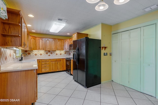 kitchen featuring light tile patterned flooring, sink, light stone countertops, decorative backsplash, and black appliances